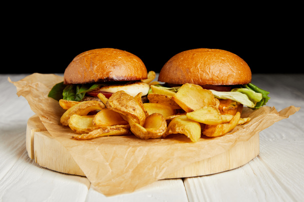 Hamburgers en Franse frietjes geserveerd op Kraft papier op witte tafel - Foto, afbeelding