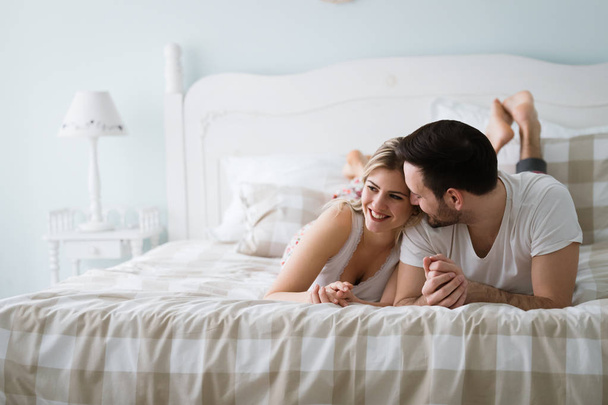 Portrait of young attractive loving couple in bedroom - Zdjęcie, obraz