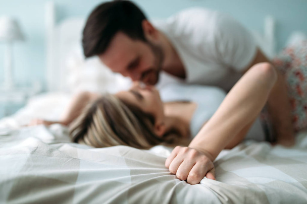 Portrait of young attractive loving couple in bedroom - Photo, image
