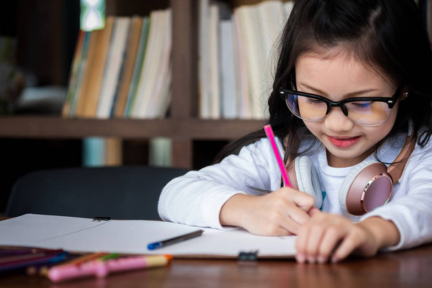 cute girl smiled and sitdown to drawing a book in the library, children concept, education concept - Photo, image