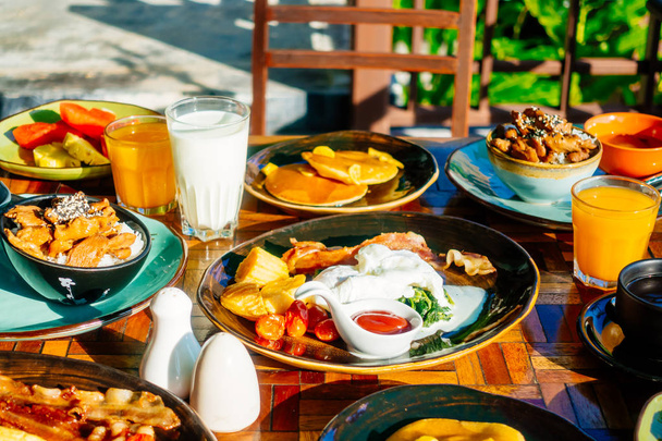 Healthy breakfast set with egg bacon pancakes orange juice milk bread coffee and other on wooden table - Photo, Image