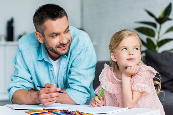 père et mignonne petite fille dessin avec crayons de couleur ensemble à la maison
  - Photo, image