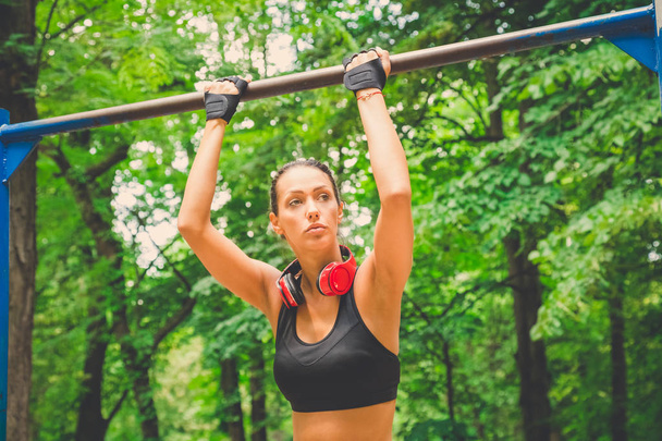 Fitness woman preparing for doing pullups in nature. Healthy lifestyle concept. - 写真・画像