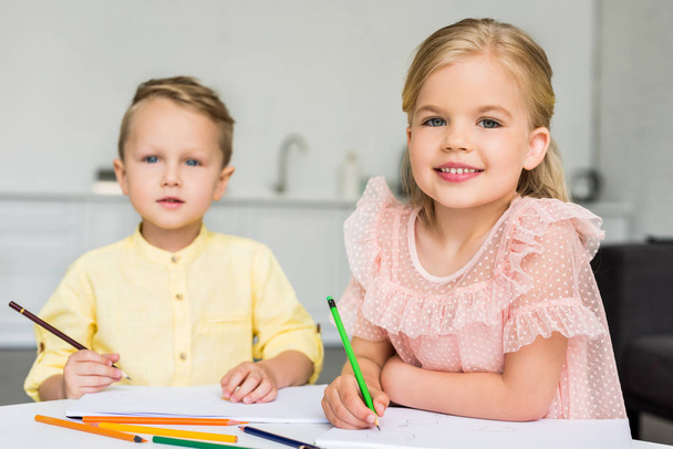 Niedliche kleine Kinder zeichnen und lächeln zu Hause in die Kamera - Foto, Bild