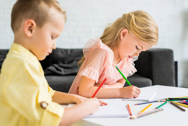 αξιολάτρευτο μικρά παιδιά σχέδιο με χρωματιστά μολύβια στο σπίτι - Φωτογραφία, εικόνα