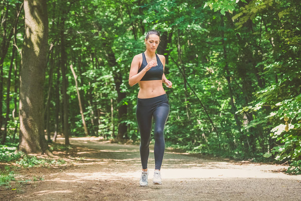 Fiatal női sportoló jogging erdőben. Kocogó csinál reggel fizikai képzés. - Fotó, kép