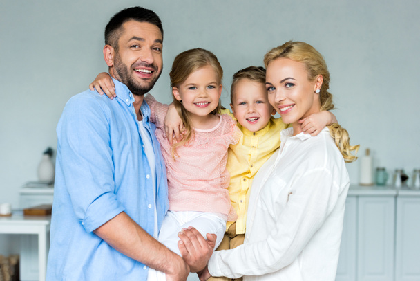 happy family with two adorable children smiling at camera together at home  - Foto, afbeelding