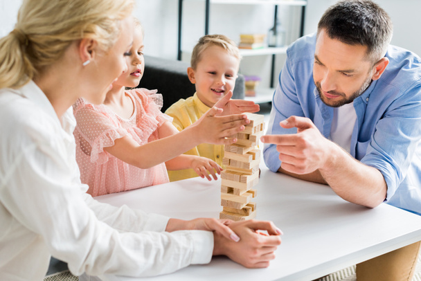 familia feliz con dos niños jugando con bloques de madera en casa
   - Foto, Imagen
