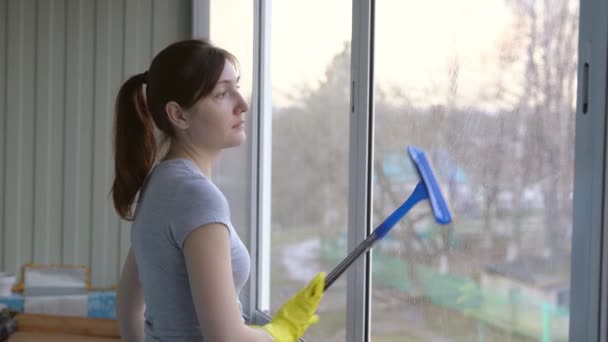 Vrouw in gele handschoenen wassen van het venster voor een speciale mop - Video