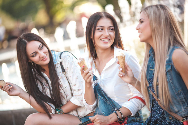 Весёлые молодые женщины веселятся у фонтана. Привлекательные девушки едят мороженое
 - Фото, изображение