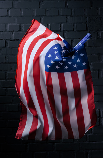 sventolando verticalmente bandiera degli Stati Uniti di fronte al muro di mattoni neri, concetto di Independence Day
 - Foto, immagini