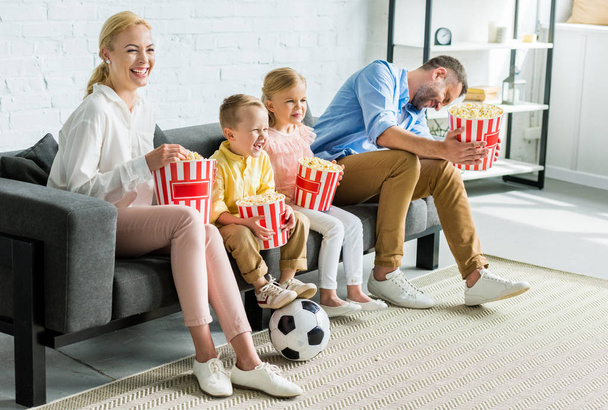 happy family eating popcorn while sitting together on sofa at home - Photo, Image