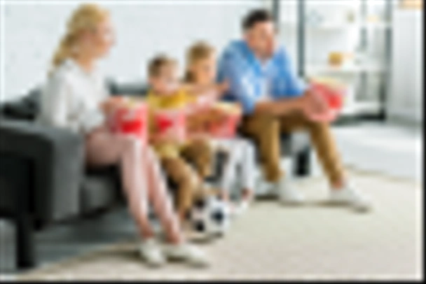 family with two kids eating popcorn and watching tv at home - 写真・画像
