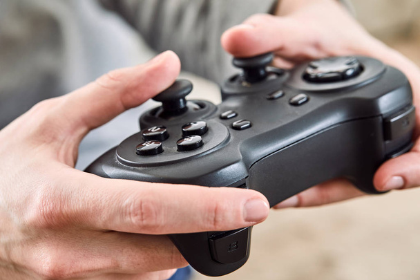 manos masculinas sosteniendo controladores de joystick mientras juega videojuegos en casa
 - Foto, Imagen