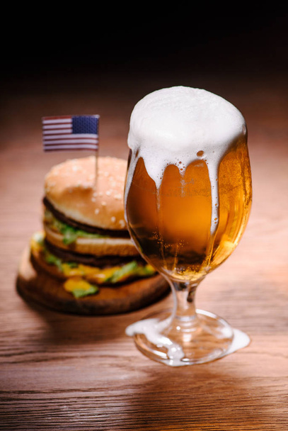 ízletes burger pohár sör a fából készült asztal - Fotó, kép