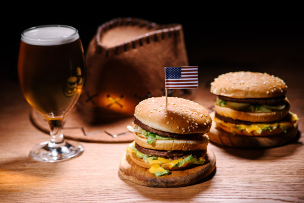 tasty burgers on wooden table with american cowboy hat and glass cold of beer - Photo, Image