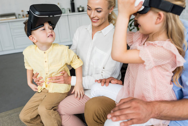 обрезанный снимок родителей, играющих с детьми с помощью наушников виртуальной реальности дома
 - Фото, изображение