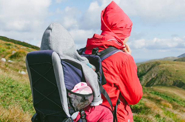 Young happy mother hold little traveller on back - baby girl in carrying backpack enjoying travel adventure, Hiking activity with child on family summer vacation, weekend nature tour - Foto, imagen