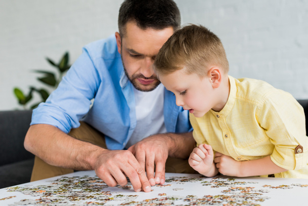 focused father and son playing with jigsaw puzzle together at home  - Zdjęcie, obraz