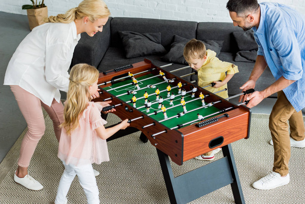 vista ad alto angolo di famiglia felice con due bambini che giocano a calcio balilla insieme a casa
  - Foto, immagini