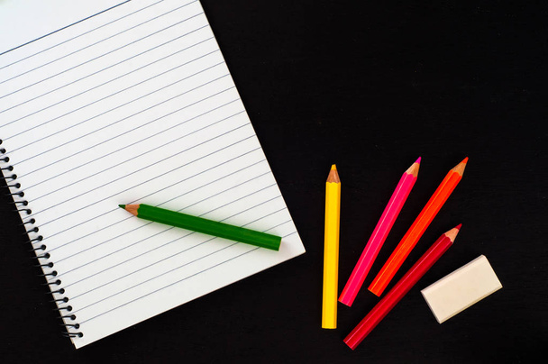 empty notebook with colorful pencils on black background  - Φωτογραφία, εικόνα