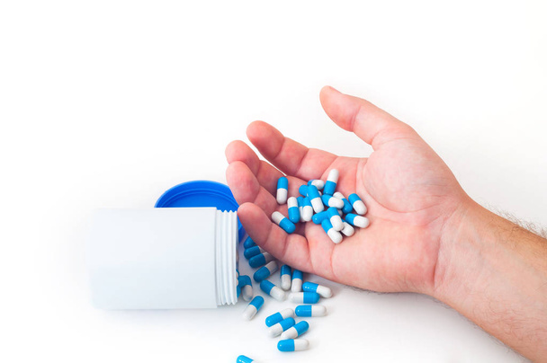 Mannenhand houden hoop pillen in de buurt van witte fles - Foto, afbeelding