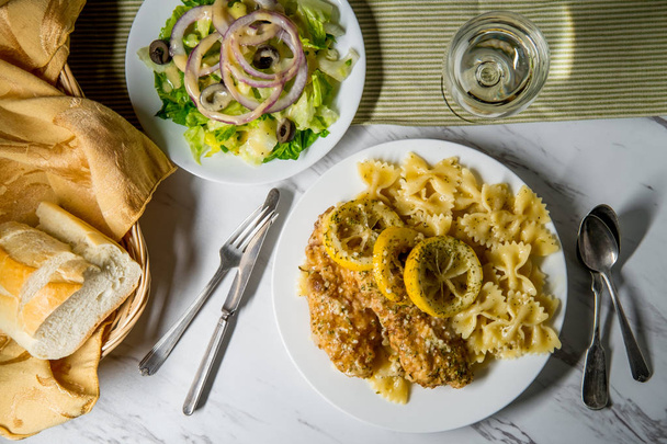 Pollo francés italiano americano con pasta de farfalle y ensalada de acompañamiento
 - Foto, Imagen