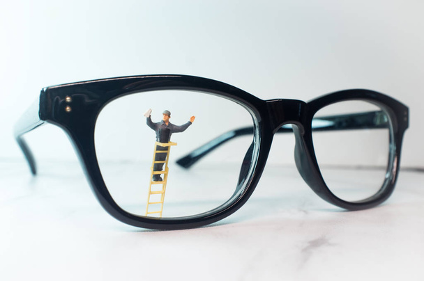 Оптические очки чистятся крошечной фигуркой, символизирующей ясное зрение - Фото, изображение