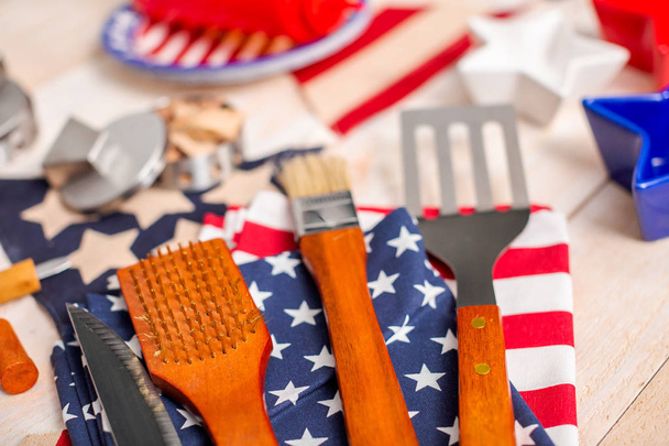 BBQ tools with July 4th decorations on wood background. - Zdjęcie, obraz