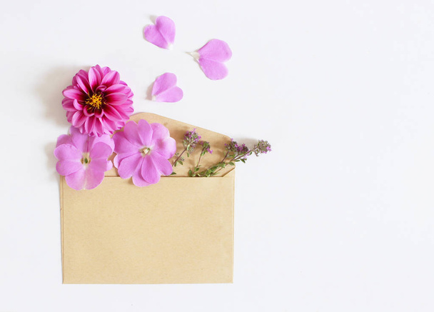 Brown envelope with a spring flower arrangement isolated on white background. Flat lay, top view. Empty space for your text. - Фото, зображення
