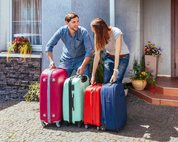 Νεαρό ζευγάρι οικογενειακά με βαλίτσα σε σπίτι φόντο. Άνδρας και γυναίκα έτοιμη για τις καλοκαιρινές διακοπές. - Φωτογραφία, εικόνα