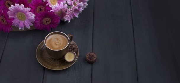 Delicious milk chocolate, a bouquet of fresh flowers and a morning aromatic coffee. Black wooden background, free space for text. Copy space. banner - Foto, afbeelding