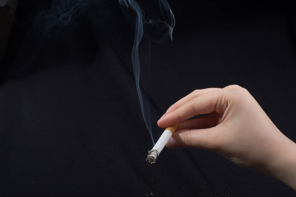 Ruka drží kouřící cigaretu s kouřem kolem - Fotografie, Obrázek
