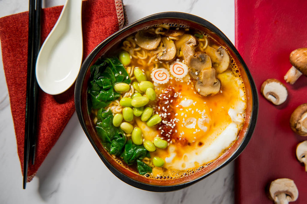 Spicy edamame and narutomaki spiral ramen noodle soup with runny fried egg - Фото, зображення