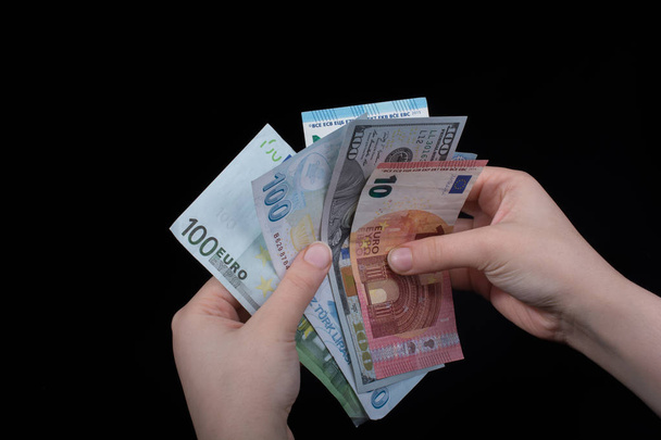 Ręczne trzymanie banknotów dolara amerykańskiego na czarnym tle - Zdjęcie, obraz