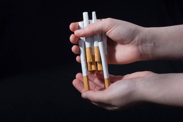 Hand verteilt Bündel Zigaretten auf schwarzem Hintergrund - Foto, Bild