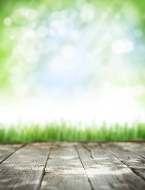 abstrakte sonnige Sommerhintergrund mit Holztisch, Gras und blauem Himmel. Kopierraum für Ihr Produkt. gemildert - Foto, Bild
