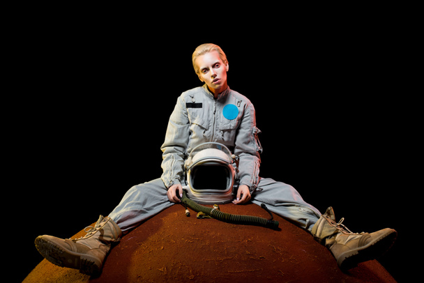 attraktive Raumfahrerin im Raumanzug mit Helm sitzt auf dem Planeten - Foto, Bild