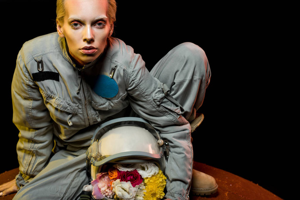 cosmonaute en combinaison spatiale avec des fleurs en casque assis sur la planète
  - Photo, image