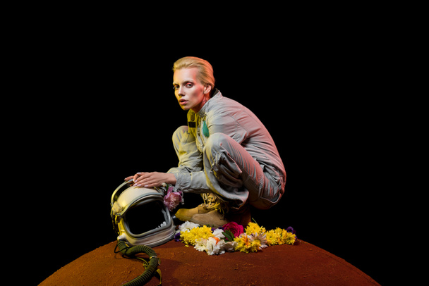 vonzó külföldi Szkafander, virágokkal és sisak ül a bolygón  - Fotó, kép