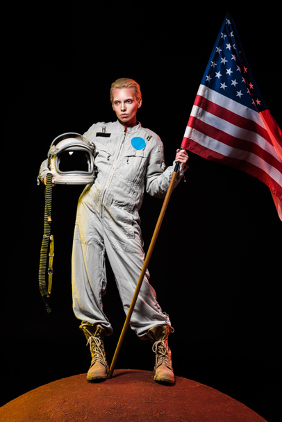 hermoso astronauta en traje espacial con casco y bandera americana en el planeta rojo
  - Foto, imagen