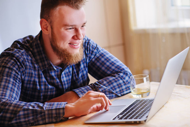 Giovane uomo sorride che lavora sul computer portatile a casa
. - Foto, immagini