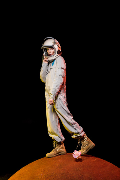kosmonaut v skafandr a helma stojí na Pivoňka květ na planetě - Fotografie, Obrázek
