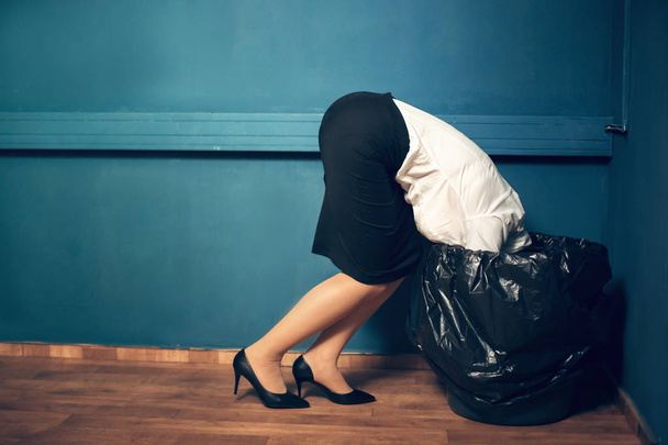 Woman with her head in garbage bin. - Foto, afbeelding