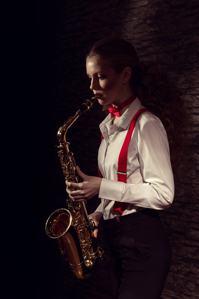 Beautiful girl with saxophone in mens dress - Foto, Bild
