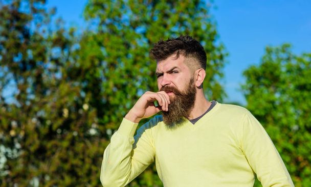 Relaxation concept. Bearded man have rest on sunny day outdoors. Man with beard and mustache on thoughtful face at balcony, trees on background, defocused. Man with long beard enjoy view from balcony - Photo, image