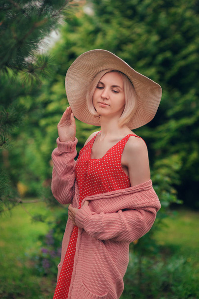 Portrait of beautiful young woman in wide beach hat, against background of summer green park - Photo, Image