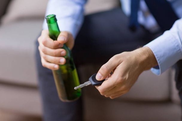 male driver hands holding beer bottle and car key - Foto, Bild