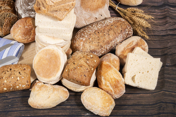 Свіжий асортимент декількох запечених сортів хліба на дерев'яному столі
. - Фото, зображення