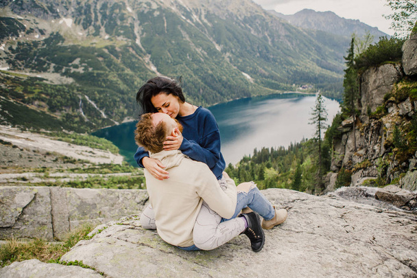 Young couple sitting at the edge of rock in norwegian fjord - 写真・画像